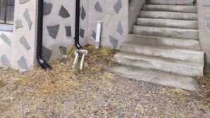 Une cabane en rondins dont l’extérieur est orné d’un motif en pierre, avec un escalier en béton et une rambarde en métal.