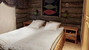 Une chambre à coucher de style cabane en bois, avec un lit, deux tables de chevet et une œuvre d’art accrochée au mur.
