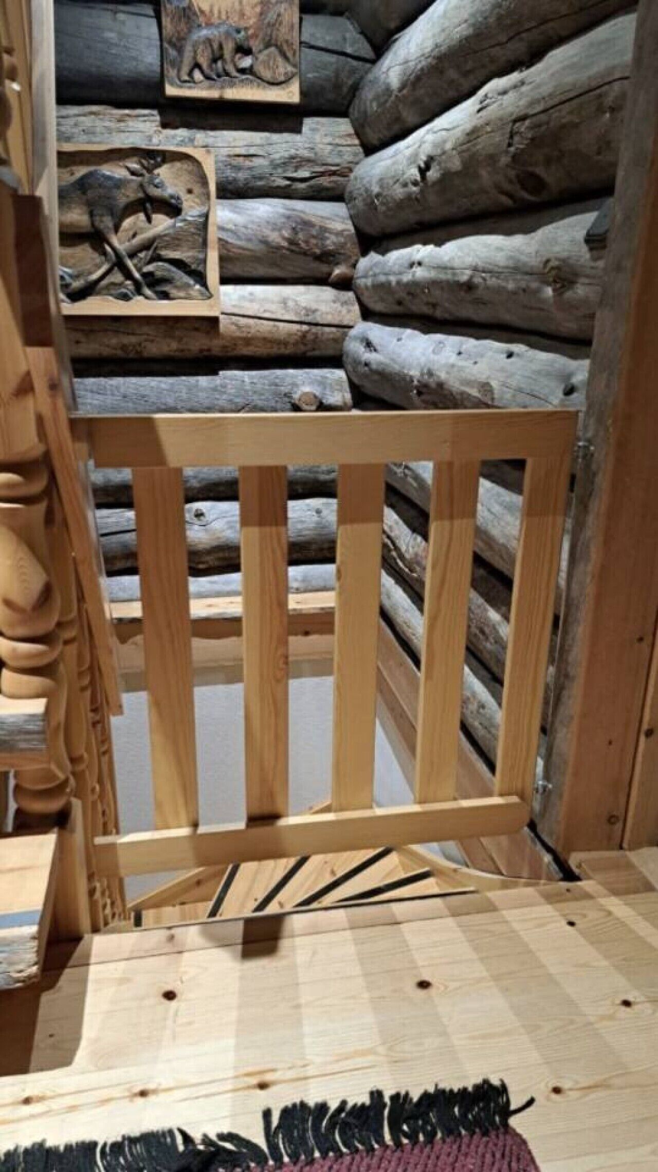 Interieur van een houten blokhut, met een wand van boomstammen, een houten bank en een vloerkleed.