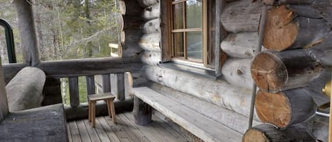 Een vakantiehuisje met een houten terras, een raam en een bankje.