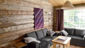 A log cabin interior with a sofa set, a small table, and a lamp. - Cozy 2BR Apt in Länsi-Ruka | Sauna & Fireplace (Ruka)