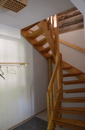 A wooden spiral staircase in a room with white walls and a ceiling vent. - Cozy 2BR Apt in Länsi-Ruka | Sauna & Fireplace (Ruka)