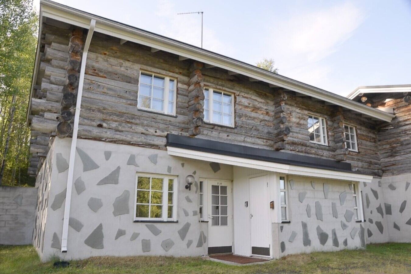 A log cabin with a stone facade, a front door, and two windows.