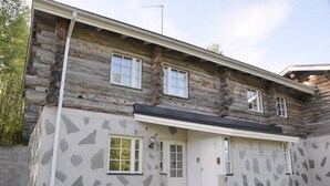 A log cabin with a stone facade, a front door, and two windows. - Cozy 2BR Apt in Länsi-Ruka | Sauna & Fireplace (Ruka)