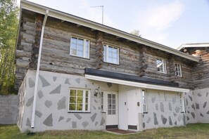 Eine Blockhütte mit Steinfassade, einer Haustür und zwei Fenstern.
