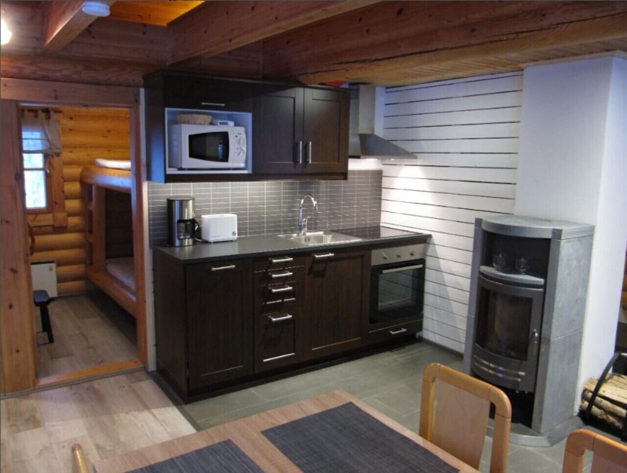 A compact kitchen with dark cabinets, a microwave, a sink, and a built-in oven.