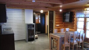Ein Holzhütten-Interieur mit Essbereich, Küchenzeile und Kamin.