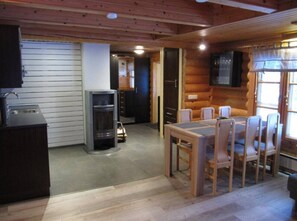 Ein Holzhütten-Interieur mit Essbereich, Küchenzeile und Kamin.
