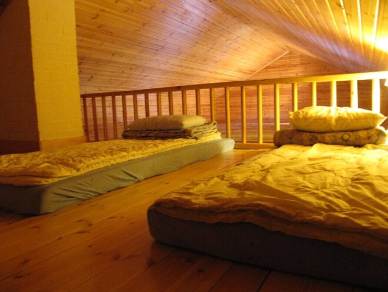 Loft sleeping area with mattresses laid out under the wooden roof.