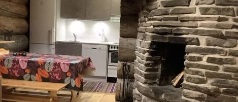 Ein rustikaler Innenraum mit Kamin aus Stein, Holzmöbeln und einer Küchenzeile.