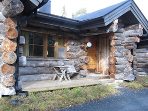 A log cabin with a wooden deck and a table. - Rantaruka | Atmospheric Apt | Sauna & Ski-Bus 100m (Ruka)