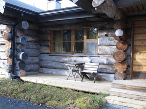 A log cabin with a porch, a table, and two chairs. - Rantaruka | Atmospheric Apt | Sauna & Ski-Bus 100m (Ruka)