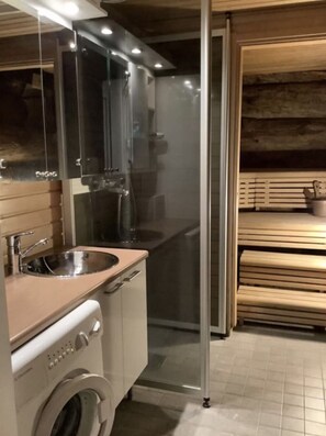 A modern kitchen with a stainless steel sink, a built-in oven, and a washing machine. - Rantaruka | Atmospheric Apt | Sauna & Ski-Bus 100m (Ruka)