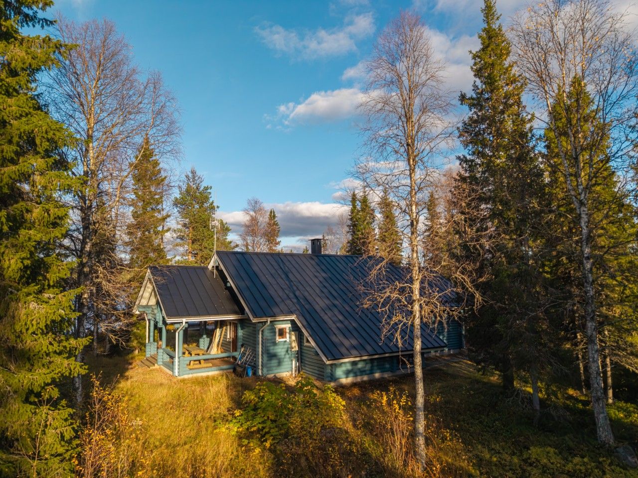 A cabin with a sloped roof, surrounded by trees, and a small porch area. - Villa Porontima | Cozy Lakeside Cabin for 12 (Kuusamo)
