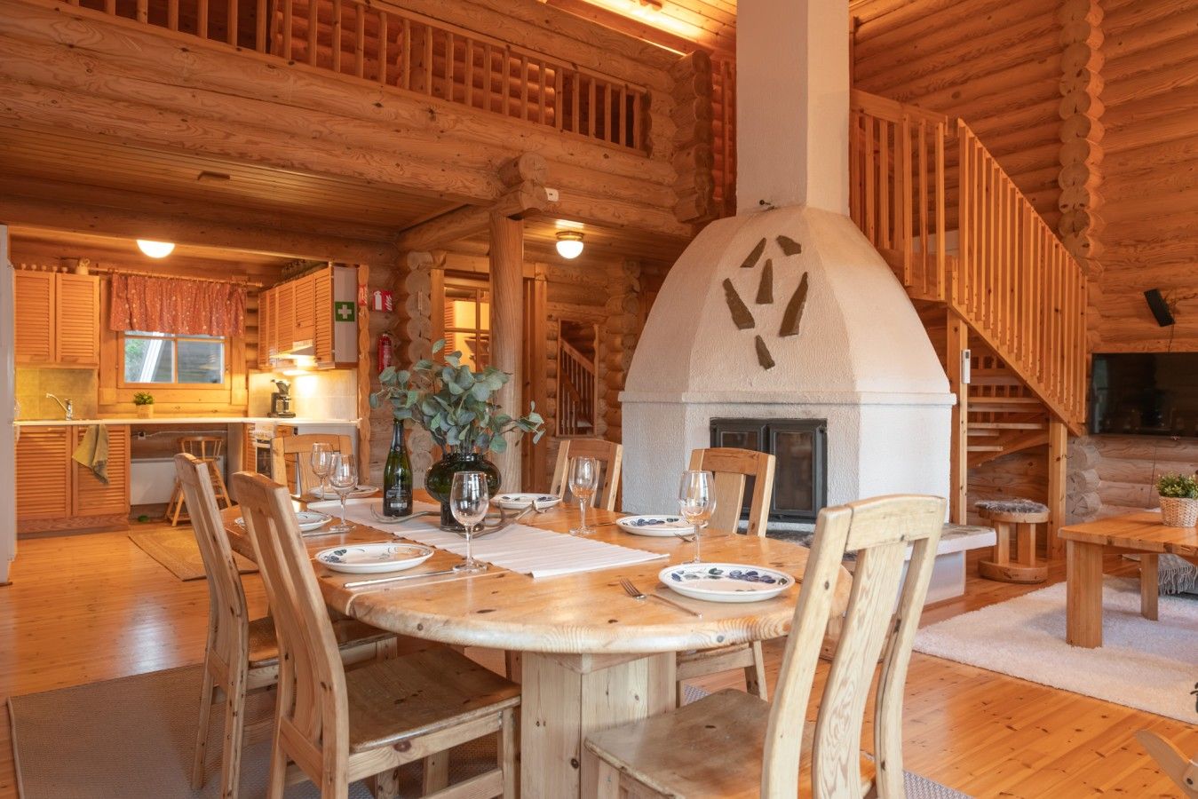 A wooden interior with a dining area, a fireplace, and a kitchen.