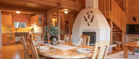 A wooden interior with a dining area, a fireplace, and a kitchen.