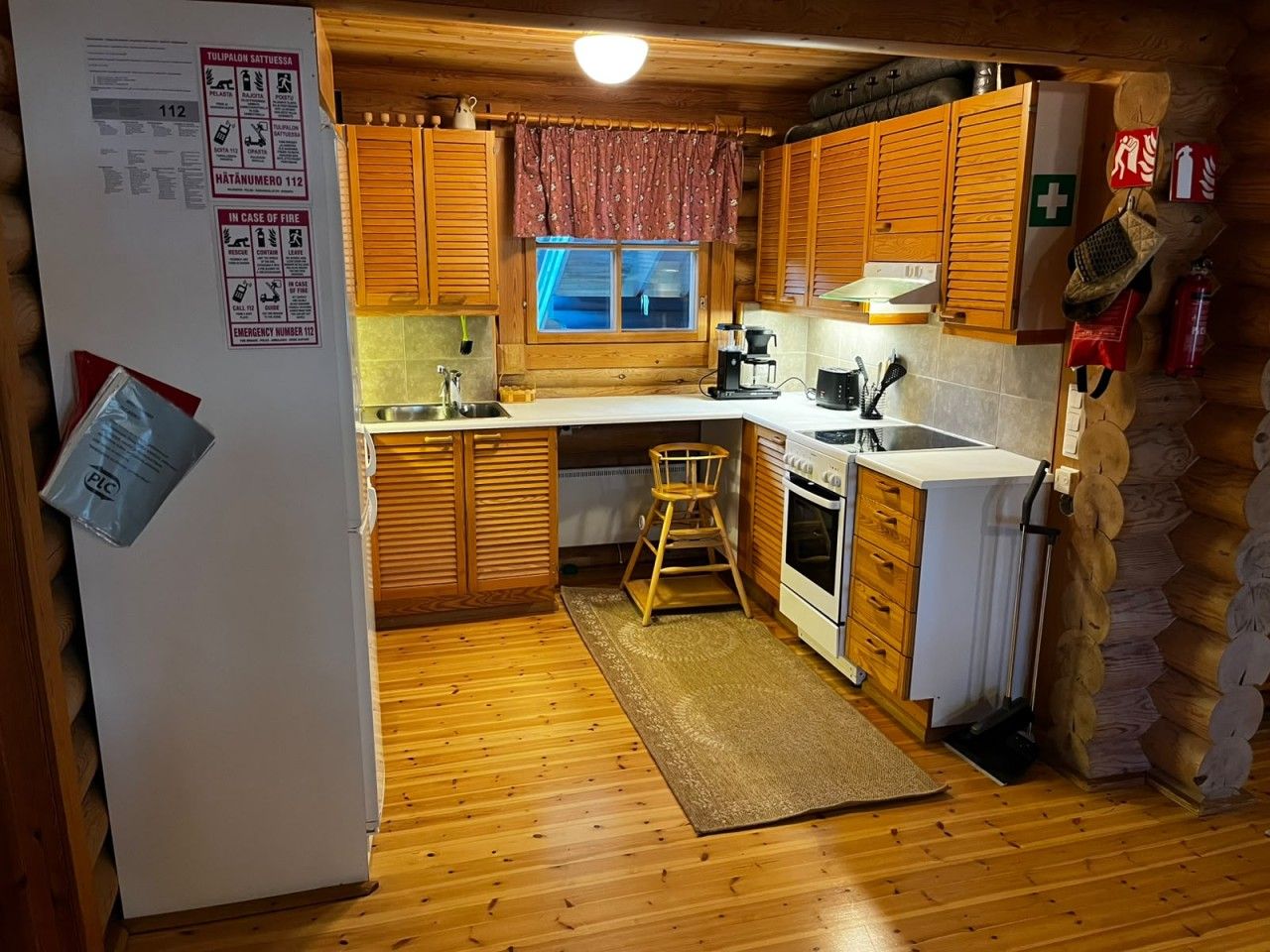 A compact kitchen with wooden cabinets, a sink, a stove, and a refrigerator.