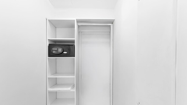 Un placard blanc avec un coffre-fort noir sur l’étagère supérieure.