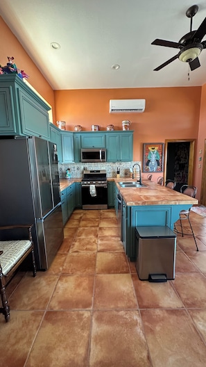 A kitchen with teal cabinets, a black refrigerator, a microwave, an oven, and a sink.
