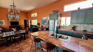 Una cocina con una isla central, mesa de comedor, sillas y un refrigerador.
