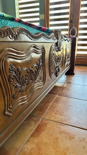 A wooden bed with intricate carvings and a metal headboard.