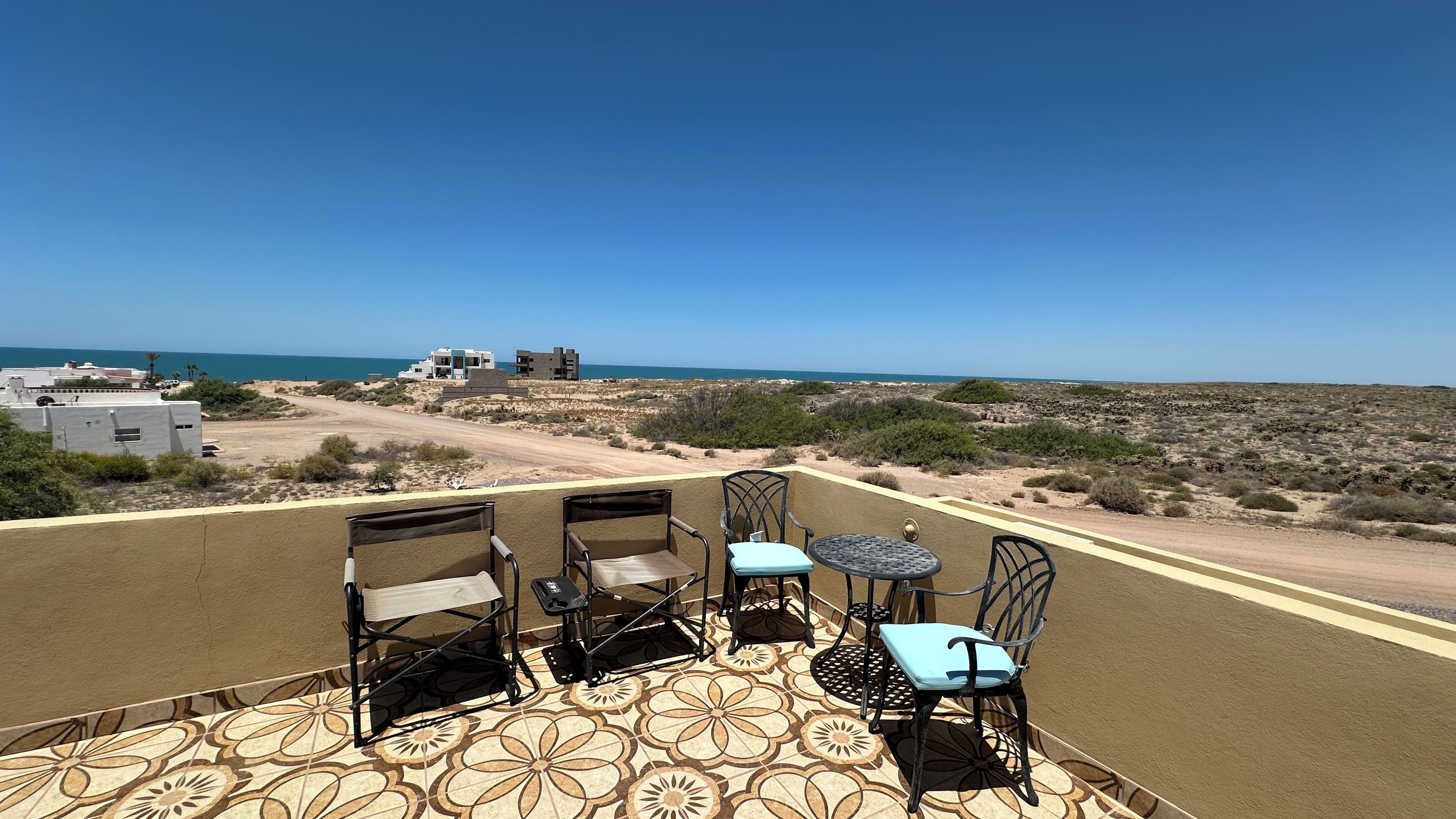 A terrace with a view of the sea, featuring a table and four chairs.