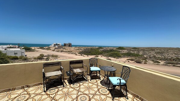 A terrace with a view of the sea, featuring a table and four chairs.