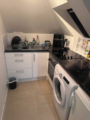 A compact kitchen with a washing machine, a coffee maker, and a sink. - 1 bedroom apartment Whetstone, north London - close to tube station (London)