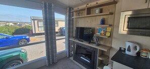 Ein Zimmer mit Kamin, Fernseher, Ventilator und Blick ins Freie.