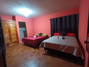 A room with two beds, a wardrobe, and a door. - Casas de Qlí (SANTIAGO ATITLÁN, SOLOLÁ)