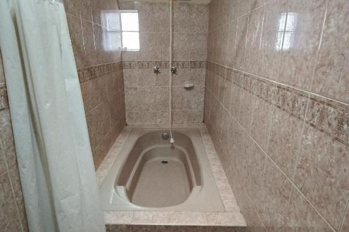 A bathroom with a bathtub, a shower, and a window.