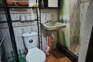 Ein Badezimmer mit Toilette, Waschbecken und Ablagen für Toilettenartikel.