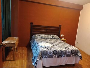 Ein Schlafzimmer mit einem hölzernen Bett, einem Nachttisch und einer Lampe.