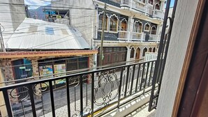 Un balcon doté d’une rambarde en métal donnant sur une rue bordée d’immeubles.