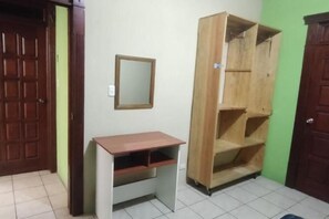 Una habitación con un escritorio de madera, un espejo y un armario de madera.