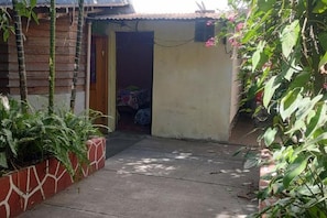 Un sendero estrecho que lleva a un edificio con fachada de madera y una puerta.