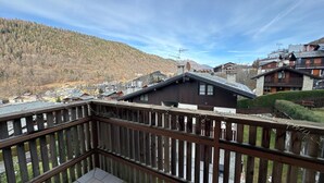 Ein Holzbalkon mit Blick auf eine gebirgige Landschaft und traditionelle Gebäude.