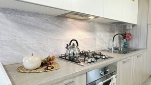 A kitchen with a gas stove, a kettle, and a sink. - Casa Lara by Ca-Sa Check (Aprica)