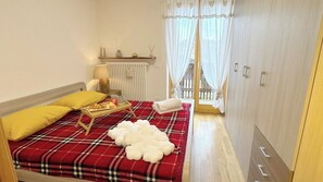 A bedroom with a bed, a bedside table with a tray of pastries, a radiator, and a window with curtains. - Casa Lara by Ca-Sa Check (Aprica)