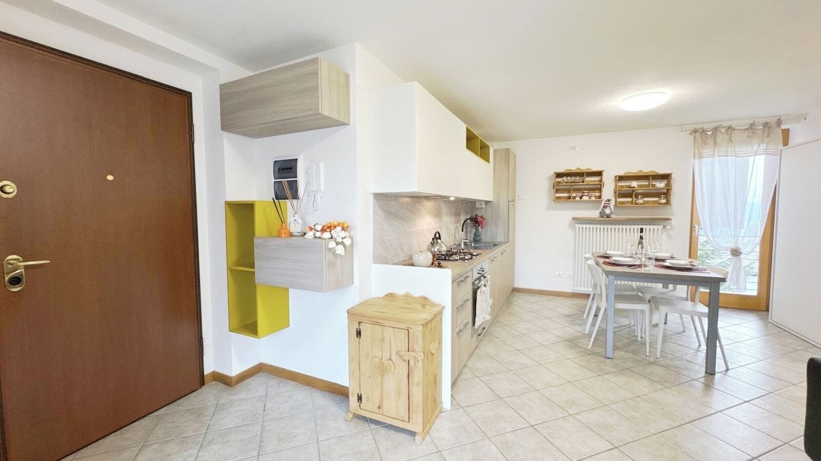 A compact kitchen with a dining area, a wooden cabinet, and a radiator.