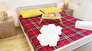 A neatly made bed with a plaid bedspread, a tray with pastries, and a white fluffy pillow. - Casa Lara by Ca-Sa Check (Aprica)