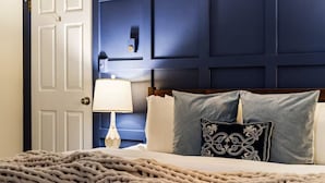 Un letto con una coperta beige, un cuscino bianco e un cuscino decorativo con motivo bianco e nero.
