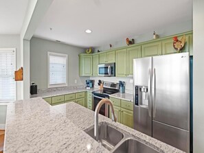 A kitchen with green cabinets, stainless steel appliances, and a granite countertop. - Wintergreens R332- Mtn Condo/View, Gated Resort, Indoor/Outdoor Pools & Hot Tub (Banner Elk)