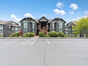 A multi-story building with a central entrance and a parking lot in front. - Wintergreens R332- Mtn Condo/View, Gated Resort, Indoor/Outdoor Pools & Hot Tub (Banner Elk)