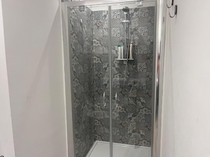 A shower enclosure with patterned tiles and a handheld showerhead.