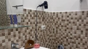 A bathroom with a large sink, a smaller sink, a mirror, a hairdryer, and a towel rack.