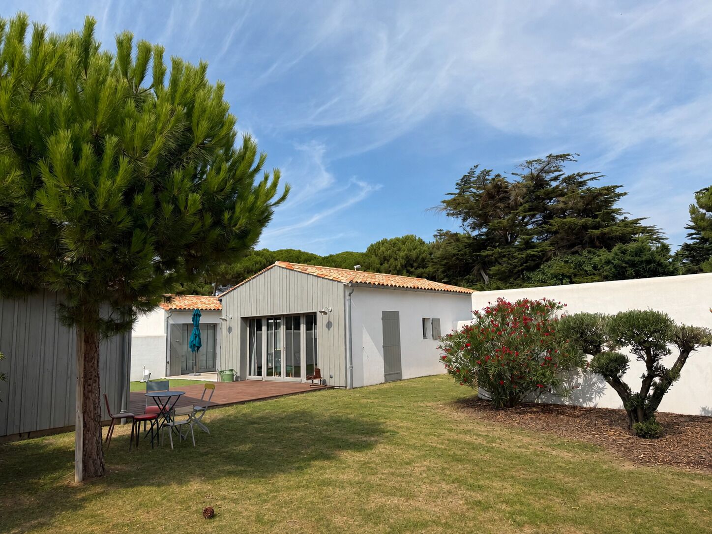 A residential property with a patio, a covered outdoor seating area, and a white building with a tiled roof.