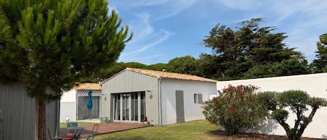 A residential property with a patio, a covered outdoor seating area, and a white building with a tiled roof.