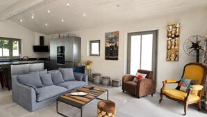 A modern living room with a grey sofa, a wooden coffee table, and a brown armchair. - ODELINE maison spacieuse et lumineuse au calme (Le Bois-Plage-en-Ré)