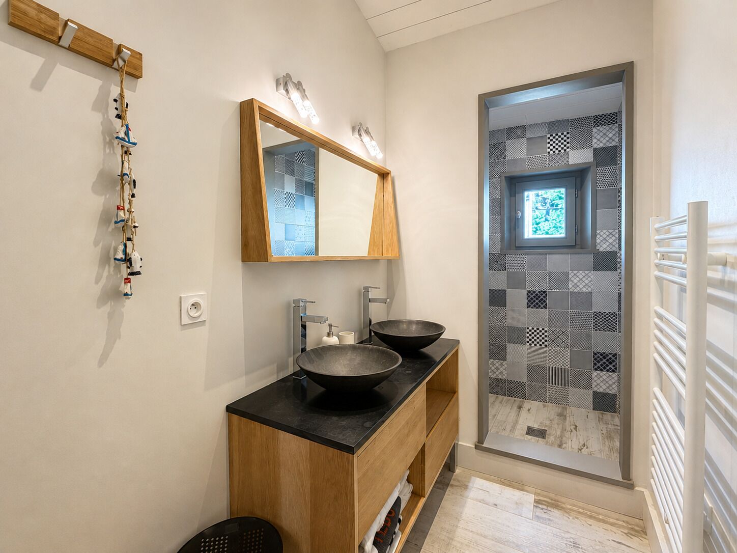 A bathroom with a wooden vanity, a large mirror, and a black basin.